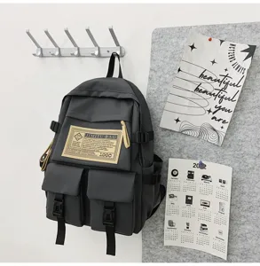 Detailansicht eines dunkelgrauen Nylon-Schulrucksacks mit Fronttaschen und stabilen Gurten.