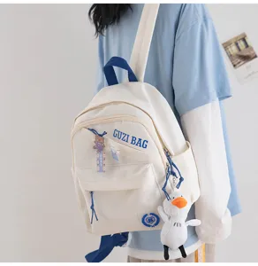 Detail shot of a cute Japanese style white and blue mini backpack with duck plush pendant.