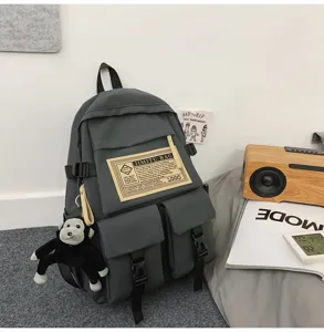 Detailansicht des dunkelgrauen Nylon-Rucksacks mit mehreren Taschen und niedlichem Affenanhänger.