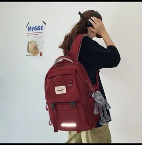 Seitenansicht des roten Rucksacks mit großem Fassungsvermögen und niedlichem Anhänger.