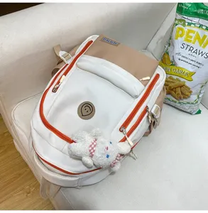 Lässiger Canvas-Rucksack in Weiß und Khaki mit orangen Reißverschlüssen und Kaninchen-Anhänger.