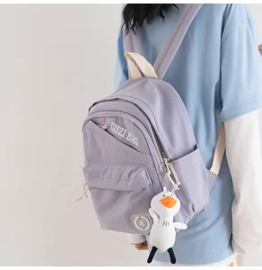 Detail of light purple mini backpack featuring diagonal zipper and cute duck plush pendant.