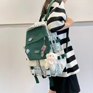 Niedlicher koreanischer Schülerrucksack in Dunkelgrün mit Graffiti-Muster und Bärenanhänger Detail.
