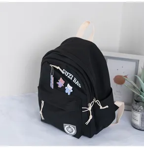 Black mini casual backpack detail view featuring zipper pocket and cute bear pendant.
