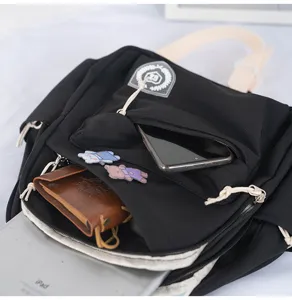 Detail view of black mini canvas backpack with multiple front pockets and badge decor.