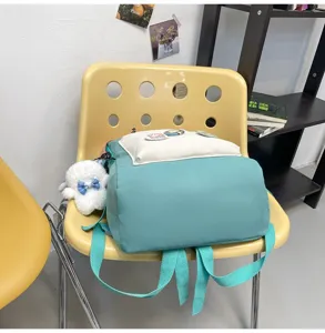 Casual color-block school backpack with cute plush pendant and front pocket for daily use.