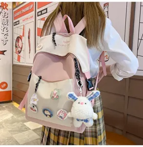 Casual pink canvas school backpack with cute plush bunny pendant and badges for students.