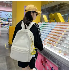 Japanese style canvas backpack detail, white student bookbag with cute flower pendant.