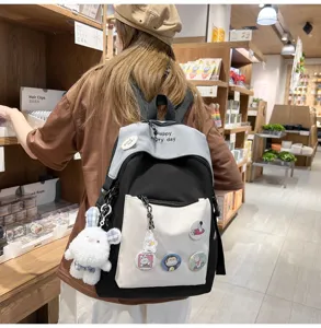 Casual multi-pocket backpack for students with cute badges and plush rabbit pendant.