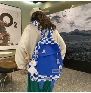 Dettaglio zaino da studente a quadretti blu con grazioso ciondolo anatra e grande spazio.