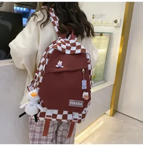 Stiloso zaino scolastico a quadri marrone con simpatici pendenti e grande capacità per studio.