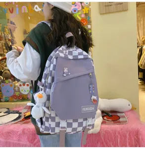 Vista dettagliata di uno zaino da studente a quadretti viola e bianchi con ciondolo in peluche.