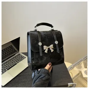 Detailed view of a stylish black retro women backpack handbag with metallic bow accent.