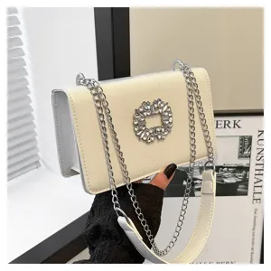 Detail shot of stylish white shoulder bag with rhinestone buckle and silver chain strap.