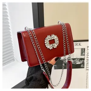 Red leather shoulder bag detail, elegant crystal buckle and silver chain strap for women.