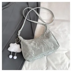 Detailed view of a trendy crumpled texture shoulder bag with a cute white cloud plush keychain charm.
