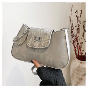 Detailansicht der grauen Marmor-Schultertasche mit Schmetterlingsverschluss und Kette.