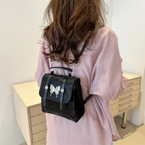 Chic black women backpack with metal butterfly decor, stylish and versatile for travel use.