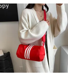 Detail view of the red nylon cylinder crossbody bag featuring white stripes and adjustable red strap.