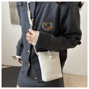 Detailed view of white mini crossbody phone bag, pearl closure, braided strap, chic style.
