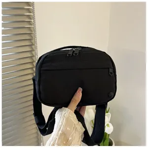 Detail shot of a casual black nylon crossbody phone bag with adjustable strap and zipper.