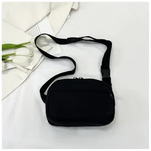 Detailed view of the black nylon crossbody bag with adjustable strap and front pocket design.