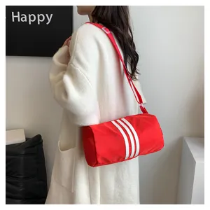 Detailed view of the red nylon barrel crossbody bag featuring classic white stripes in scene.