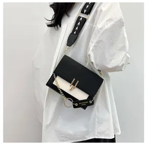 Detail view of stylish colorblock crossbody bag with wide strap and chain ornament.