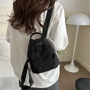 Casual black nylon mini backpack worn on back, stylish minimalist travel daypack for women.