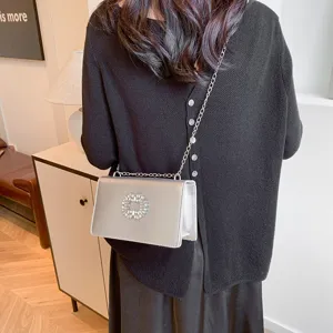Stylish metallic silver shoulder bag with crystal buckle and chain strap for women.