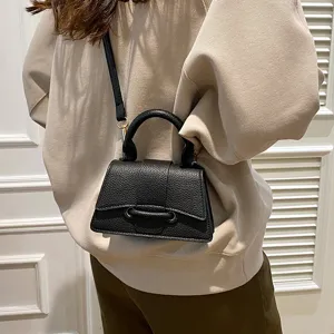 Black textured leather top handle crossbody bag for women, stylish curved design for daily wear.