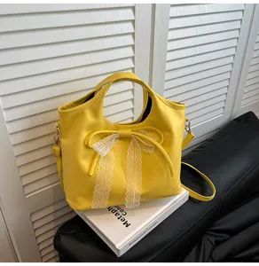 Detailed close-up of the yellow handbag featuring an elegant lace bow and handle design.