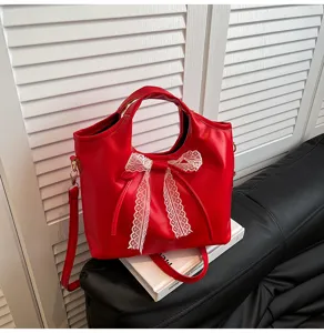 Details of red PU leather handbag featuring white lace bow and gold hardware in scene.
