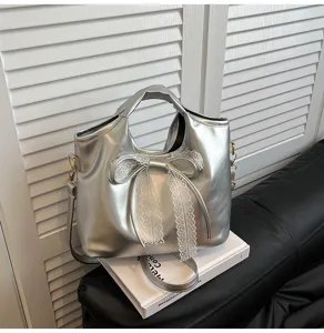 Silver metallic shoulder handbag detail featuring elegant white lace bow, premium styling view.