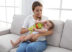 Interactive green animal hand puppet toy shown in cozy family scene for early learning.