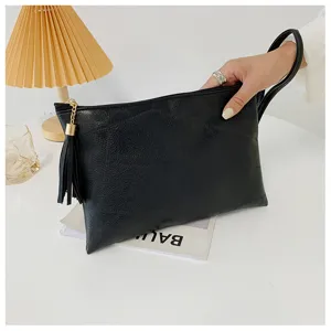 Élégante pochette en similicuir noir pour femme avec pompon élégant et dragonne pratique.