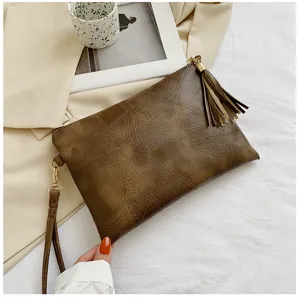 Sac pochette rétro en cuir PU pour femme avec gland chic et dragonne, texture élégante.