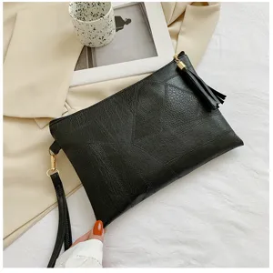 Sac pochette noir pour femme texture geometrique avec pompon et dragonne tendance.