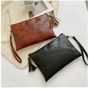 Gros-plan détail pochette rétro texturée pour femme en marron et noir avec pompons en cuir.