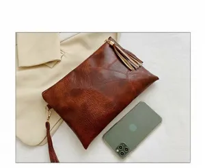 Vue de détail d'une pochette marron rétro texturée, avec pompon et design plissé.