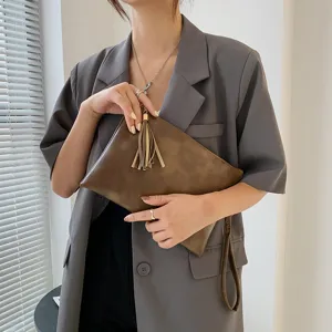 Sac pochette femme texture rétro avec pompon et dragonne pour la mode automne hiver.