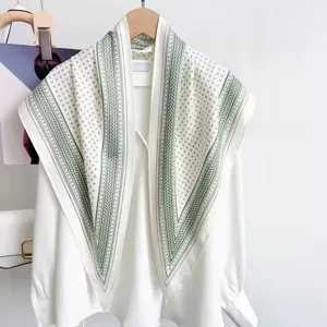 Detailed view of the elegant green and white printed triangular scarf shawl on white shirt.