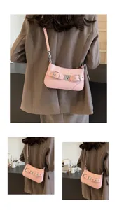 Sac à épaule rose à motif croco détail montrant la jolie boucle en cœur et la sangle.