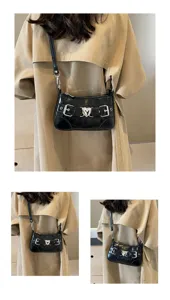 Vue détaillée du sac porté épaule noir motif crocodile avec boucle de cœur en métal.