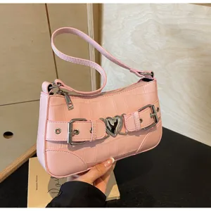 Détail de sac porté épaule cuir motif croco rose avec boucle cœur et double sangle.