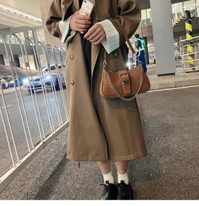 Borsa a spalla marrone in camoscio sottobraccio con catena in metallo e fibbia, stile vintage.