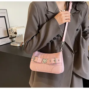 Élégant sac sous les bras rose motif crocodile avec boucle cœur, belle photo de détail.