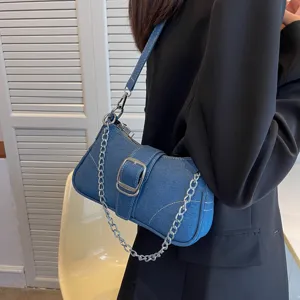 Vista dettagliata di una borsa a tracolla in denim blu con fibbia e catena in metallo.