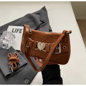 Détail de sac à bandoulière motif crocodile marron, élégante boucle cœur de niche.