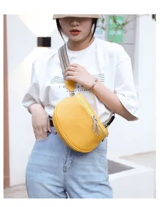 Detailed view of genuine leather yellow saddle bag with wide strap and metal zippers for women.